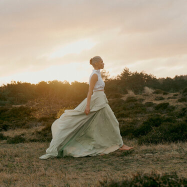 Woman walking across a meadow at sunrise